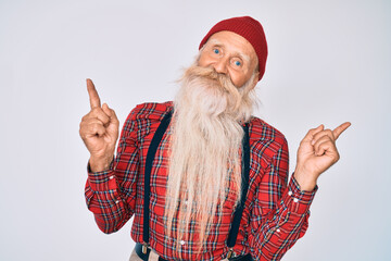 Old senior man with grey hair and long beard wearing hipster look with wool cap smiling confident pointing with fingers to different directions. copy space for advertisement