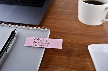 There's dummy documents, a cup of coffee and a notebook with a sticky note stuck to it that says Official Development Assistance.