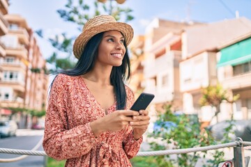 Fototapeta premium Young african american tourist woman on vacation smiling happy using smartphone at the city.