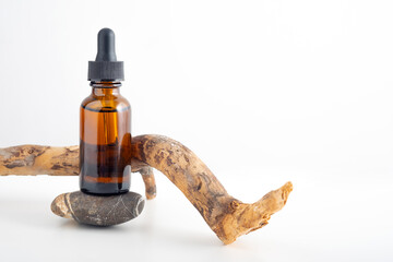 Mockup cosmetic face serum brown glass bottle with a pipette on a stylish minimalist white background with tree bark, wood, snag, sandalwood decor. Female beauty concept, empty template, essential oil