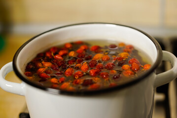rose hips are brewed in a saucepan on a gas stove