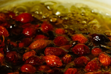 close-up of rose hips are brewed in a saucepan on a gas stove
