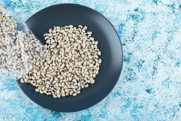 White raw beans on black plate