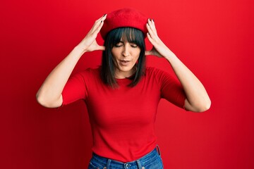 Young hispanic woman wearing french look with beret with hand on head for pain in head because stress. suffering migraine.