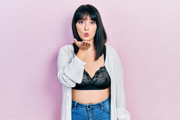 Young hispanic woman wearing lingerie looking at the camera blowing a kiss with hand on air being lovely and sexy. love expression.