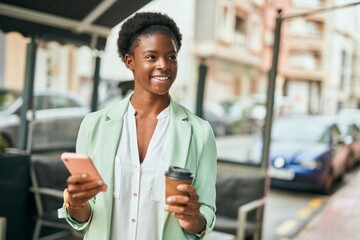 Young african american businesswoman using smartphone drinking coffee at the city.