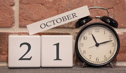 Important date, October 21, autumn season. Calendar made of wood on a background of a brick wall. Retro alarm clock as a time management concept.