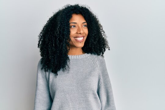African american woman with afro hair wearing casual winter sweater looking to side, relax profile pose with natural face and confident smile.
