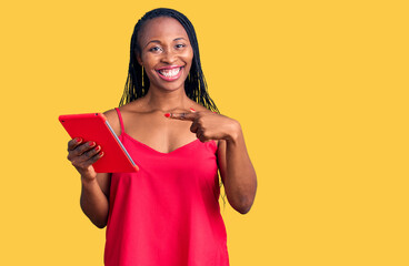 Young african american woman holding touchpad smiling happy pointing with hand and finger