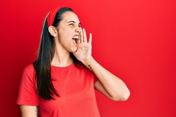 Fototapeta premium Young hispanic woman wearing casual red t shirt shouting and screaming loud to side with hand on mouth. communication concept.
