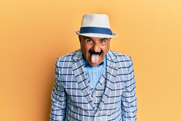 Mature middle east man with mustache wearing vintage and elegant fashion style sticking tongue out happy with funny expression. emotion concept.
