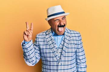 Mature middle east man with mustache wearing vintage and elegant fashion style smiling with happy face winking at the camera doing victory sign. number two.