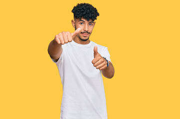 Fototapeta na wymiar Young arab man wearing casual white t shirt approving doing positive gesture with hand, thumbs up smiling and happy for success. winner gesture.