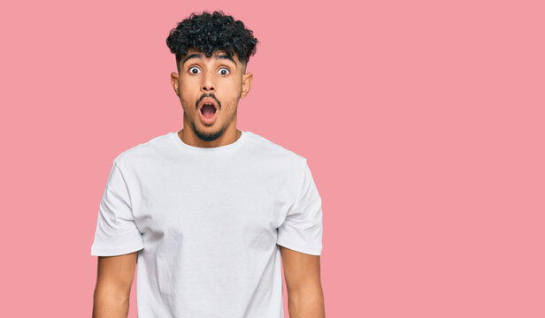 Young arab man wearing casual white t shirt afraid and shocked with surprise and amazed expression, fear and excited face.