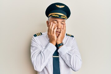 Handsome middle age mature man wearing airplane pilot uniform tired hands covering face, depression and sadness, upset and irritated for problem