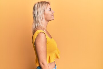 Young blonde girl wearing casual clothes looking to side, relax profile pose with natural face and...