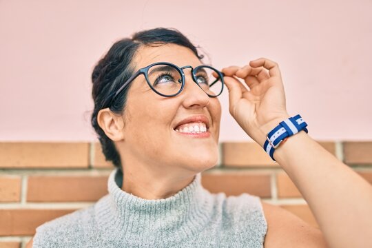 Young plus size woman smiling happy leaning on the wall at the city.