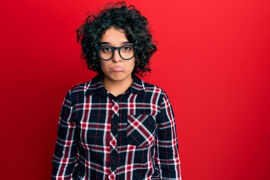 Young hispanic woman with curly hair wearing casual clothes and glasses depressed and worry for distress, crying angry and afraid. sad expression.