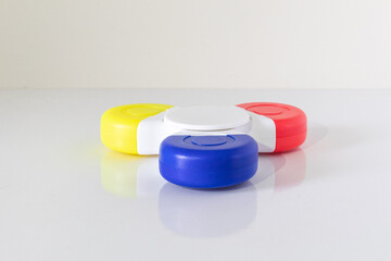 Yellow, blue and red fidget spinner laying on a white backgroud without spinning. Front view