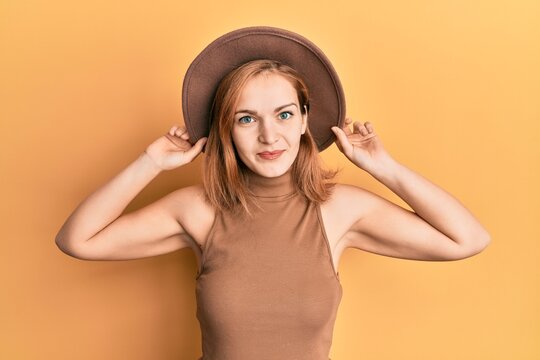 Young caucasian woman wearing hat relaxed with serious expression on face. simple and natural looking at the camera.