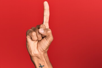 Hand of hispanic man over red isolated background counting number one using index finger, showing idea and understanding