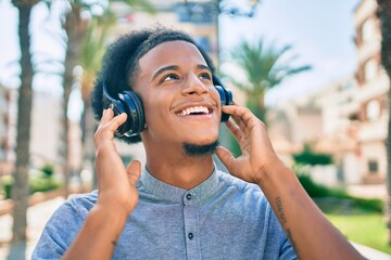 Young african american man listening to music using headphones at the city.