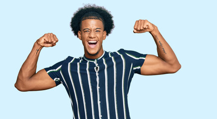African american man with afro hair wearing casual clothes showing arms muscles smiling proud. fitness concept.