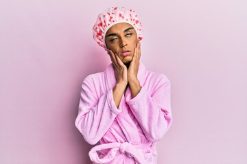 Hispanic man wearing make up wearing shower towel cap and bathrobe tired hands covering face, depression and sadness, upset and irritated for problem