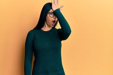 Young caucasian woman wearing casual clothes and glasses surprised with hand on head for mistake,...
