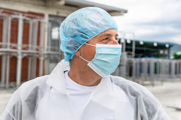 Portrait of caucasian man wearing protective mask and bouffant mob cap - Young male doctor or scientist at work in front of the laboratory hospital front view in day copy space