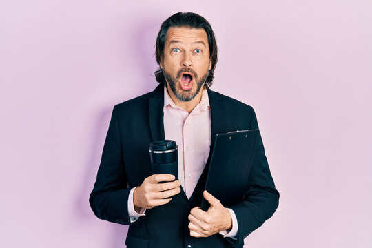 Middle age caucasian man wearing business clothes drinking a take away cup of coffee afraid and shocked with surprise and amazed expression, fear and excited face.