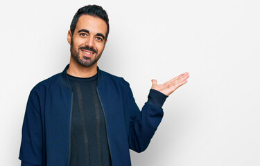 Young hispanic man wearing casual clothes smiling cheerful presenting and pointing with palm of...