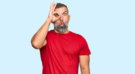 Middle age handsome man wearing casual clothes doing ok gesture shocked with surprised face, eye looking through fingers. unbelieving expression.