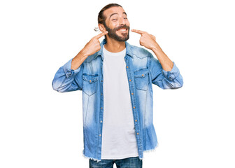 Attractive man with long hair and beard wearing casual denim jacket smiling cheerful showing and pointing with fingers teeth and mouth. dental health concept.