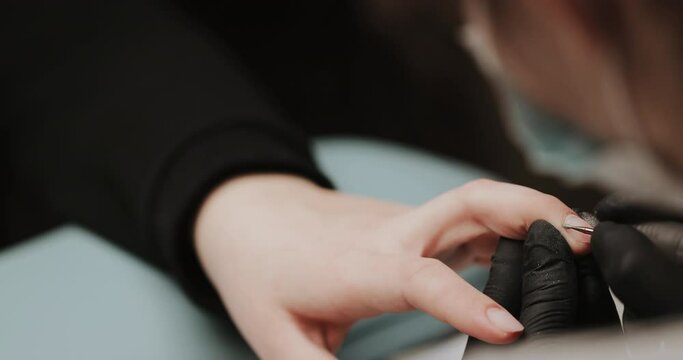 The manicurist cleans the cuticle of the nails with the device. Cuticle removal using a machine with a cutter. Professional manicure in the salon close-up.