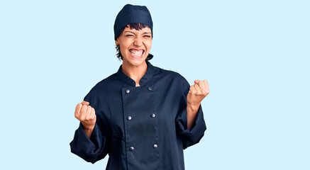 Young brunette woman with short hair wearing professional cook uniform excited for success with...
