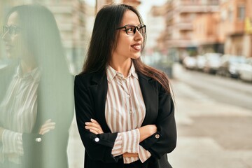 Young hispanic businesswoman smiling happy standing at the city.