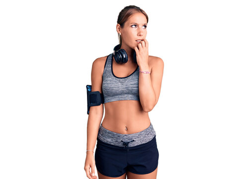 Young beautiful hispanic woman wearing gym clothes and using headphones looking stressed and nervous with hands on mouth biting nails. anxiety problem.