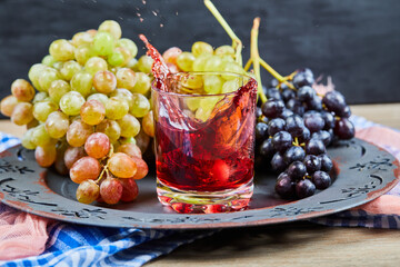 Bunch of grapes and a glass of juice on dark background