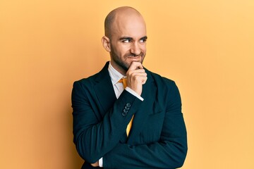 Young hispanic man wearing business suit and tie with hand on chin thinking about question, pensive expression. smiling with thoughtful face. doubt concept.