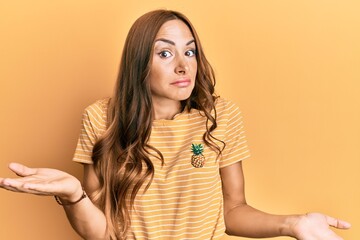 Young brunette woman wearing casual clothes clueless and confused expression with arms and hands...
