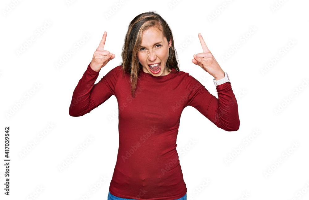 Sticker Young blonde woman wearing casual clothes shouting with crazy expression doing rock symbol with hands up. music star. heavy music concept.