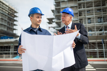 Architect and site manager discussing about a drawing