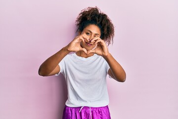 Beautiful african american woman with afro hair wearing sportswear smiling in love doing heart symbol shape with hands. romantic concept.