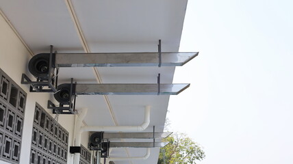 Ventilation ducts under the eaves. Several silver pipes suck the air in the canteen kitchen to provide ventilation on the white sky background with a copy area. Selective focus