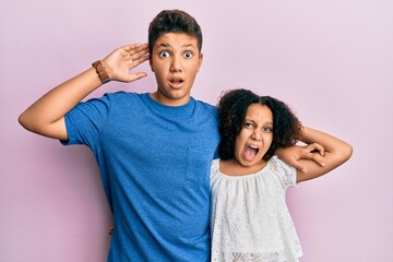 Young hispanic family of brother and sister wearing casual clothes together crazy and scared with hands on head, afraid and surprised of shock with open mouth