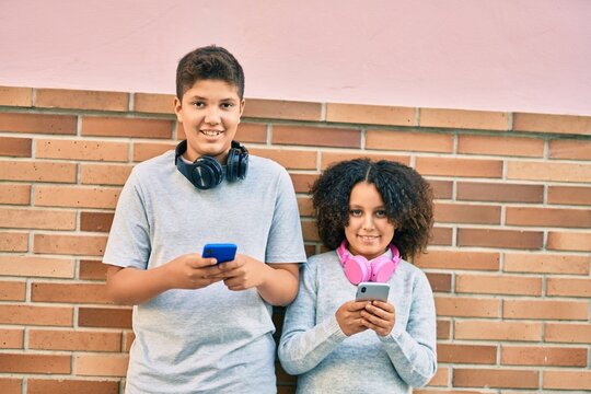 Adorable latin brother and sister smiling happy using smartphone at the city.