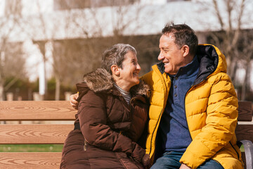 Fototapeta premium Lovely senior couple sitting on a bench in the park on a sunny day