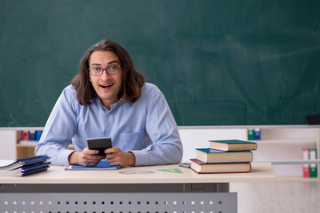 Young male teacher in front of green board