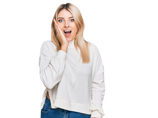 Young caucasian woman wearing casual winter sweater afraid and shocked, surprise and amazed expression with hands on face